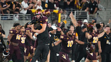 Oct 11, 2024; Tempe, Arizona, USA; Arizona State Sun Devils quarterback Sam Leavitt (10) jumps into the arms of head coach Kenny Dillingham after the the Sun Devils upset the (16) Utah Utes 27-19 at Mountain America Stadium. Mandatory Credit: Rob Schumacher-Arizona Republic