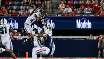 Aug 30, 2025; Tucson, Arizona, USA; Arizona Wildcats wide receiver Tre Spivey (12) catches the ball while Hawaii Rainbow Warriors defensive back Elijah Palmer (4) fails to intercept during the first quarter of the game at Arizona Stadium. Mandatory Credit: Aryanna Frank-Imagn Images