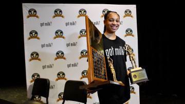 Taliah Scott holds the Florida Dairy Farmers Miss Basketball award with the names of past winners as