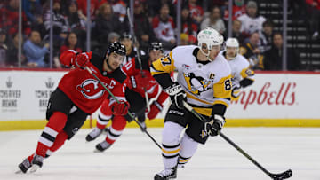 Dec 21, 2024; Newark, New Jersey, USA; Pittsburgh Penguins center Sidney Crosby (87) skates with the puck while being pursued by New Jersey Devils center Nico Hischier (13) during the first period at Prudential Center. Mandatory Credit: Ed Mulholland-Imagn Images