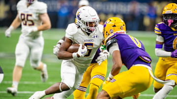 An Edna Karr defender (purple) prepares to tackle Alexandria RB JT Lindsey in the 2024 championship game won handily by the Cougars.