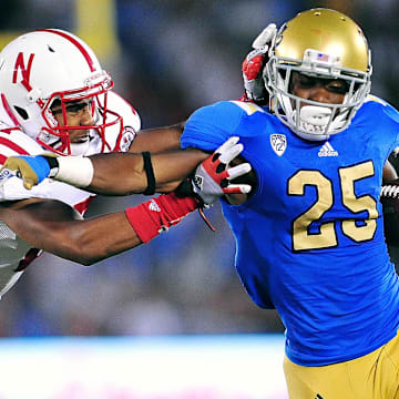 September 8, 2012; Pasadena, CA, USA; UCLA Bruins wide receiver Damien Thigpen (25) runs the ball against the defense of Nebraska Cornhuskers cornerback Ciante Evans (17) during the second half at the Rose Bowl. Mandatory Credit: Gary A. Vasquez-Imagn Images