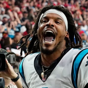 Carolina Panthers quarterback Cam Newton yells \"I'm back!\" after scoring a rushing touchdown against the Arizona Cardinals in a game in 2021.