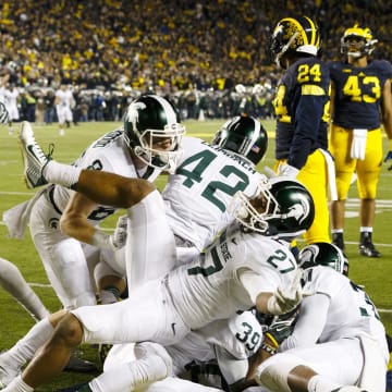 Oct 17, 2015; Ann Arbor, MI, USA; Michigan State Spartans defensive back Jalen Watts-Jackson (20) is mobbed by teammates after scoring a touchdown as the clock expires in the fourth quarter against the Michigan Wolverines at Michigan Stadium. Michigan State 27-23. Mandatory Credit: Rick Osentoski-USA TODAY Sports