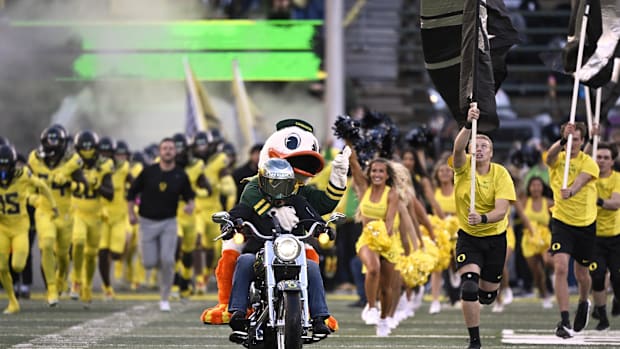 The Oregon Ducks mascot rides out to the field on a motorcycle as the football team takes the field