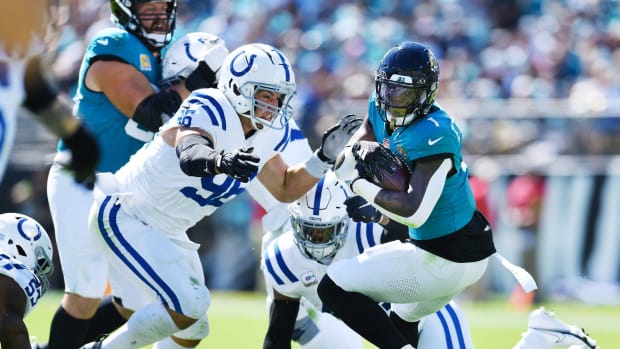 A Colts defender (Taven Bryan) is tackling a Jaguars (teal uniform) while wearing an all-white uniform and helmet.