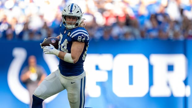 Colts tight end Tyler Warren (blue and white uniform) runs with the football after securing a catch.