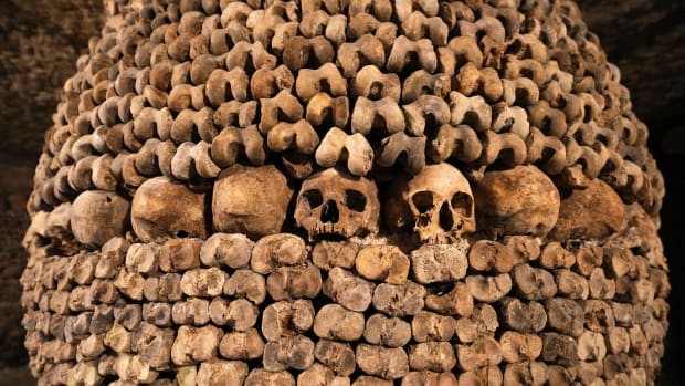 Catacombs in Paris with bones and skulls lining the passageways and walls.