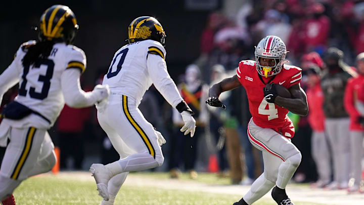 Ohio State Buckeyes wide receiver Jeremiah Smith (4) catches a pass in front of Michigan Wolverines defensive end Josaiah Stewart (0) during the second half of the NCAA football game at Ohio Stadium in Columbus on Saturday, Nov. 30, 2024. Michigan won 13-10.