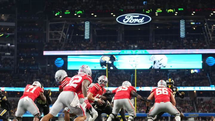 Dec 29, 2023; Arlington, Texas, USA; Ohio State Buckeyes quarterback Lincoln Kienholz (12) hands off to running back TreVeyon Henderson (32) during the second quarter of the Goodyear Cotton Bowl Classic against the Missouri Tigers at AT&T Stadium.