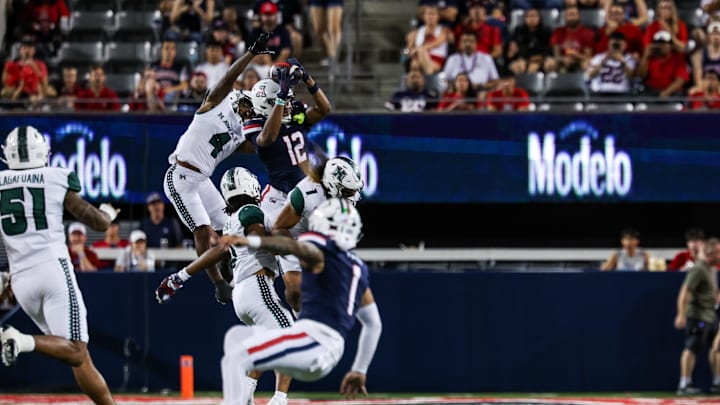 Aug 30, 2025; Tucson, Arizona, USA; Arizona Wildcats wide receiver Tre Spivey (12) catches the ball while Hawaii Rainbow Warriors defensive back Elijah Palmer (4) fails to intercept during the first quarter of the game at Arizona Stadium. Mandatory Credit: Aryanna Frank-Imagn Images