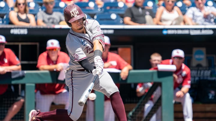 Jun 22, 2022; Omaha, NE, USA; Texas A&M Aggies catcher Troy Claunch (12) hits a single against the Oklahoma Sooners during the second inning at Charles Schwab Field. Mandatory Credit: Dylan Widger-USA TODAY Sports