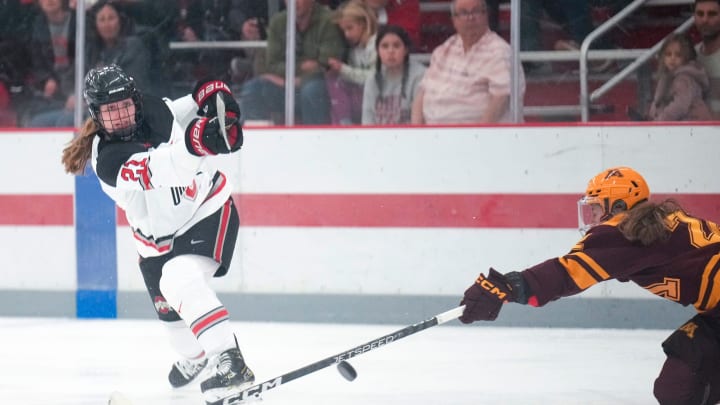 Oct 29, 2022; Columbus, Ohio, USA;  University of Minnesota forward Grace Zumwinkle (12) attempts to block Ohio State University defenseman Sydney Morrow   s (21) shot during the third period at Ohio State Ice Rink. Mandatory Credit: Joseph Scheller-The Columbus Dispatch

Hockey Osu Women Hockey