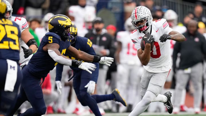 Nov 25, 2023; Ann Arbor, Michigan, USA; Ohio State Buckeyes wide receiver Xavier Johnson (0) runs past Michigan Wolverines defensive end Josaiah Stewart (5) during the second half of the NCAA football game at Michigan Stadium. Ohio State lost 30-24.