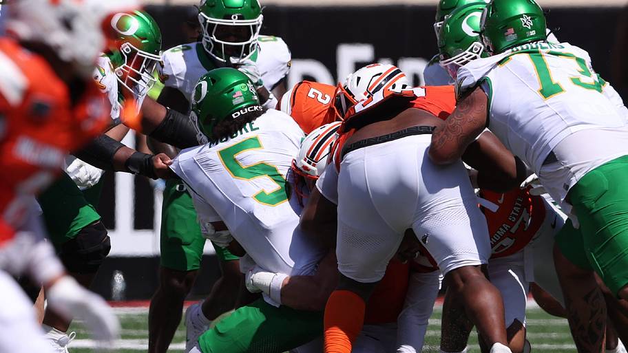 Oregon Ducks quarterback Dante Moore is tackled by the Oklahoma State Cowboys defense.
