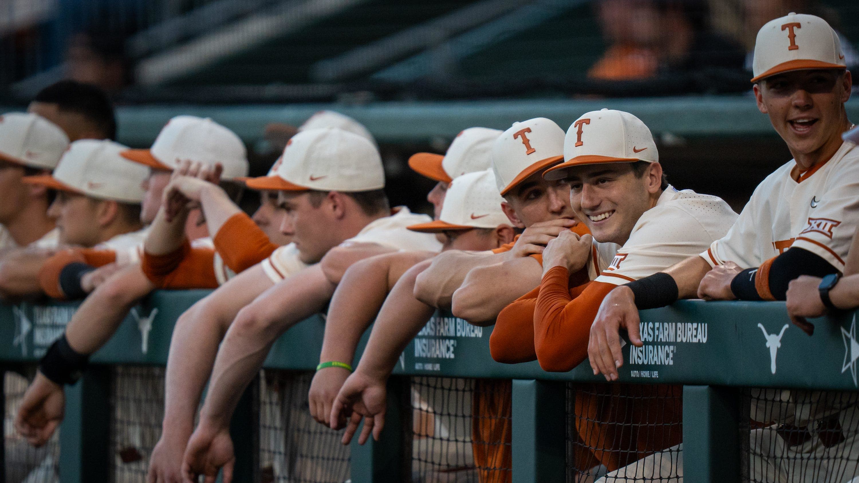 The Texas dugout smile and chat ahead of the Longhorns' game against the Texas A&M Aggies at the