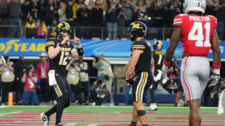 Dec 29, 2023; Arlington, Texas, USA; Missouri Tigers quarterback Brady Cook (12) pretends to take a photo of running back Cody Schrader (7) after he scored a touchdown during the third quarter of the Goodyear Cotton Bowl Classic against the Ohio State Buckeyes at AT&T Stadium. Ohio State lost 14-3.
