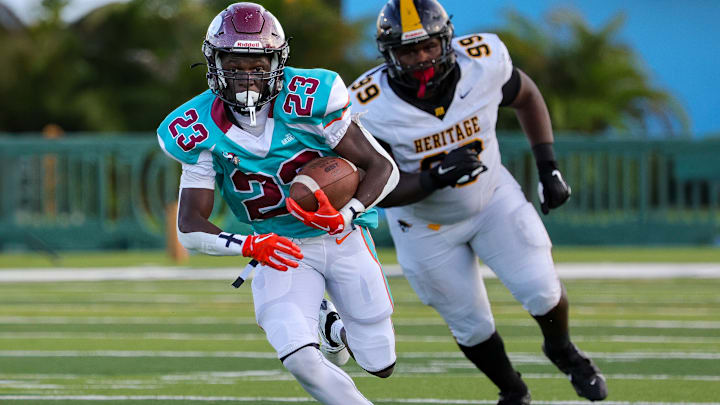 Miami Norland's Maurice Clark (23) races for yardage as American Heritage's Freddie King (99) pursues.