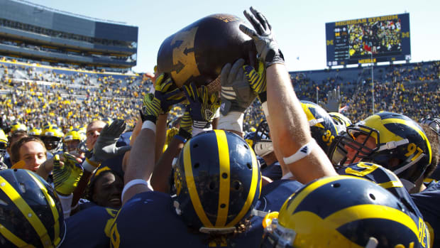 Michigan Wolverine players hold up the Little Brown Jug after the game against the Minnesota Golden Gophers.