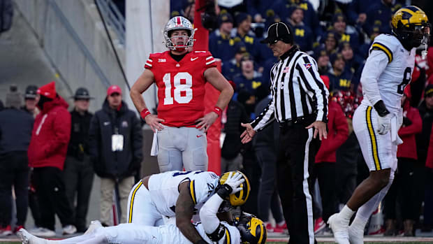 Ohio State quarterback Will Howard reacts as Michigan Wolverines players celebrate a fourth down stop to seal the game.