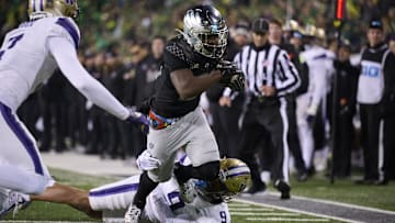 Nov 30, 2024; Eugene, Oregon, USA; Oregon Ducks running back Da'Jaun Riggs (21) picks up a first down during the second half as he breaks a tackle against Washington Huskies cornerback Thaddeus Dixon (9) at Autzen Stadium. Mandatory Credit: Troy Wayrynen-Imagn Images
