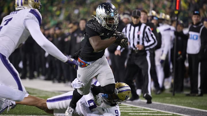Nov 30, 2024; Eugene, Oregon, USA; Oregon Ducks running back Da'Jaun Riggs (21) picks up a first down during the second half as he breaks a tackle against Washington Huskies cornerback Thaddeus Dixon (9) at Autzen Stadium. Mandatory Credit: Troy Wayrynen-Imagn Images