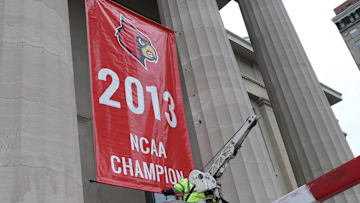 Adam Hightower hangs a replica 2013 NCAA National Championship banner on Louisville Metro Hall