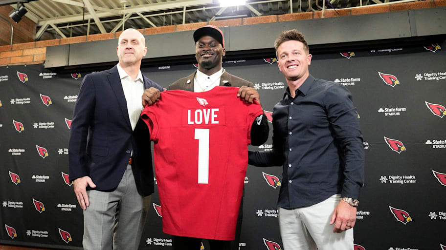 Jeremiyah Love holds a Cardinals jersey at a press conference.