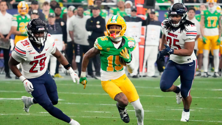 Oregon Ducks wide receiver Tez Johnson (15) carries the ball against Liberty Flames safety A'Khori Jones (29) in the first half during the Fiesta Bowl at State Farm Stadium in Glendale on Jan. 1, 2024.