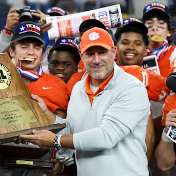 Head coach Bill Elliott of Celina (left) proudly holds the trophy following his team's victory over Kilgore in the Texas 4A Division 1 title game at AT&T Stadium. Celina enters the 2025 season ranked in our Top 25. 