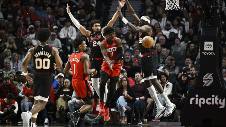 Apr 12, 2024; Portland, Oregon, USA; Houston Rockets guard Aaron Holiday (0) passes the ball during the second half against Portland Trail Blazers forward Justin Minaya (24) and center Duop Reath (26) at Moda Center. Mandatory Credit: Troy Wayrynen-USA TODAY Sports