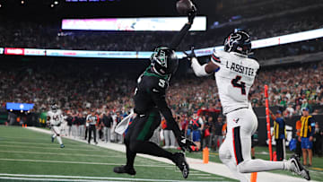 Oct 31, 2024; East Rutherford, New Jersey, USA; New York Jets wide receiver Garrett Wilson (5) catches a touchdown pass while being defended by Houston Texans cornerback Kamari Lassiter (4) during the second half at MetLife Stadium. 