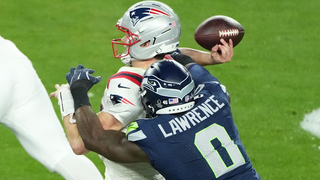 New England Patriots quarterback Drake Maye (10) is hit as he throws by Seattle Seahawks defensive end DeMarcus Lawrence (0).