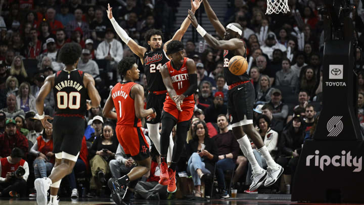Apr 12, 2024; Portland, Oregon, USA; Houston Rockets guard Aaron Holiday (0) passes the ball during the second half against Portland Trail Blazers forward Justin Minaya (24) and center Duop Reath (26) at Moda Center. Mandatory Credit: Troy Wayrynen-USA TODAY Sports