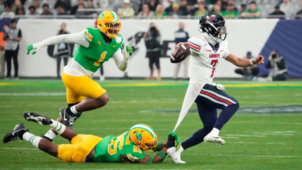 Oregon Ducks linebacker Devon Jackson (26) hangs onto the jersey of Liberty Flames quarterback Kaidon Salter (7)