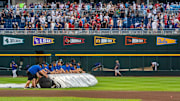 Jun 16, 2025; Omaha, Neb, USA; Grounds crew tarp the field during a storm delay in the fourth inning between the UCLA Bruins and the LSU Tigers at Charles Schwab Field. Mandatory Credit: Dylan Widger-Imagn Images