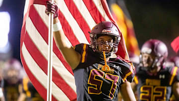 Sep 29, 2023; Phoenix, AZ, USA; Mountain Pointe Pride offensive lineman Aaron Thomas (57) holds an American flag as he runs onto the field prior to the game against the American Leadership Academy Patriots at Mountain Pointe High School  s football field in Phoenix on Sept. 29, 2023.