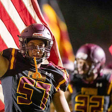 Sep 29, 2023; Phoenix, AZ, USA; Mountain Pointe Pride offensive lineman Aaron Thomas (57) holds an American flag as he runs onto the field prior to the game against the American Leadership Academy Patriots at Mountain Pointe High School  s football field in Phoenix on Sept. 29, 2023.