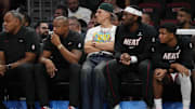 Oct 17, 2025; Miami, Florida, USA;  Miami Heat guard Tyler Herro, center, looks on from the bench as he continues to heal from foot surgery at Kaseya Center. Mandatory Credit: Jim Rassol-Imagn Images