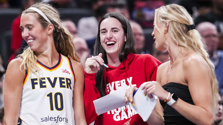 Indiana Fever guards Lexie Hull, Caitlin Clark, and Sophie Cunningham laugh near the team bench during a game against the Washington Mystics.