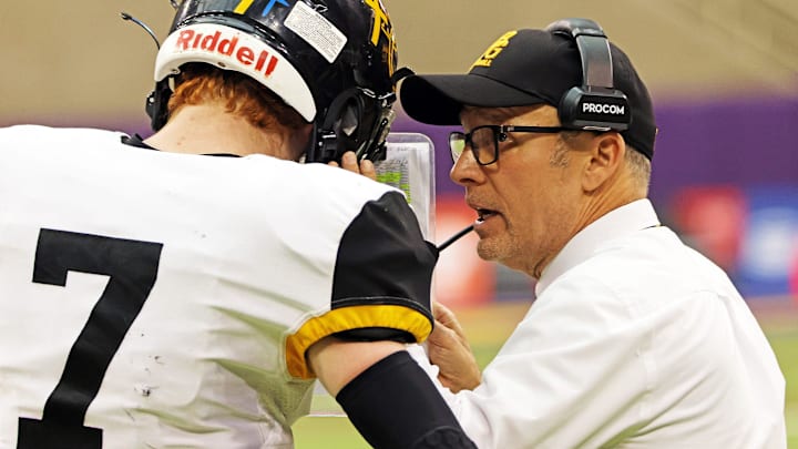 Bishop Garrigan (Algona) sophomore quarterback Tate Foertsch (7) listens to Bishop Garrigan (Algona) Head Coach Marty Wadle as the Bishop Garrigan (Algona) Golden Bears compete against the Bedford Bulldogs for the Eight-Player championship on Thursday, November 16, 2023 at the UNI-Dome in Cedar Falls.