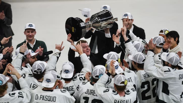 Michigan State hockey coach Adam Nightingale hoists the Big Ten tournament championship trophy after