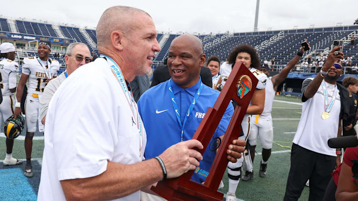 American Heritage head coach Mike Smith holds the FHSAA Class 4A state championship trophy on Dec. 13, 2025, at Pitbull Stadium in Miami after the Patriots won 33-28. Smith has been selected as the head coach of the East Team at the 2026 Navy All-American Bowl on Jan. 10.