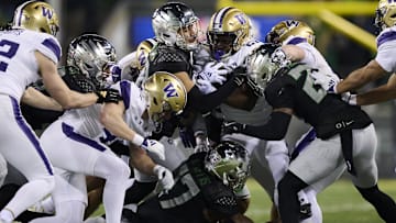 Nov 30, 2024; Eugene, Oregon, USA; Washington Huskies running back Daniyel Ngata (21) carries the ball as he is stopped by Oregon Ducks defensive back Peyton Woodyard (12) during the second half at Autzen Stadium. Mandatory Credit: Troy Wayrynen-Imagn Images