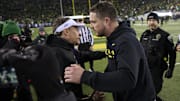 Nov 30, 2024; Eugene, Oregon, USA; Washington Huskies head coach Jedd Fisch, left, congratulates Oregon Ducks head coach Dan Lanning on his win after a game at Autzen Stadium. Mandatory Credit: Troy Wayrynen-Imagn Images