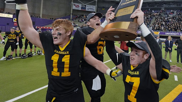 Bishop Garrigan fullback/linebacker Ethan Marso (11), center/offensive line Kayden Graves (60) and quarterback/defensive back Tate Foertsch (7) celebrate with trophy after winning 44-42 over Woodbine in the 8-players state football championship on Nov. 20, 2025, at UNI Dome in Cedar Falls, Iowa.