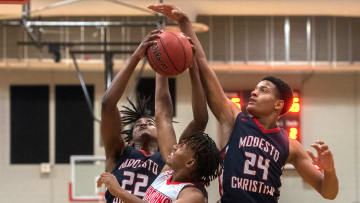 Lincoln's Beau Blackman, center, fights for a rebound with Modesto Christian's Myles Clayton, left, and Jamari Phillips during a boys varsity basketball game at Lincoln High School  in Stockton.