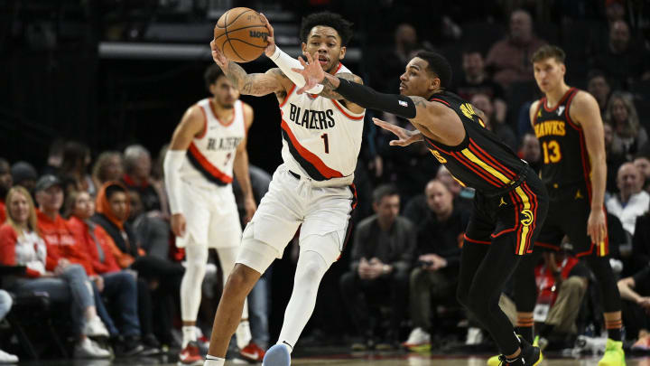 Mar 13, 2024; Portland, Oregon, USA; Atlanta Hawks guard Dejounte Murray (5) attempts to steal the basketball during the first half against Portland Trail Blazers guard Anfernee Simons (1) at Moda Center. 