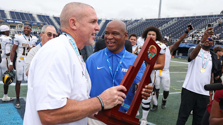 American Heritage head coach Mike Smith holds the FHSAA Class 4A state championship trophy on Dec. 13, 2025, at Pitbull Stadium in Miami that the Patriots won 33-28. Smith will be the head coach of the East Squad at the Navy All-American Bowl on Jan. 10.