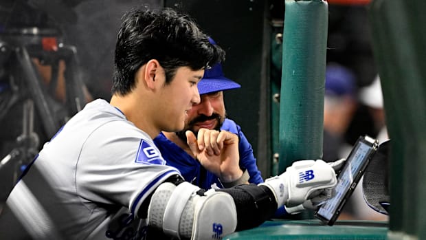 Shohei Ohtani of the Los Angeles Dodgers looks over a iPad with hitting coach Robert Van Scoyoc
